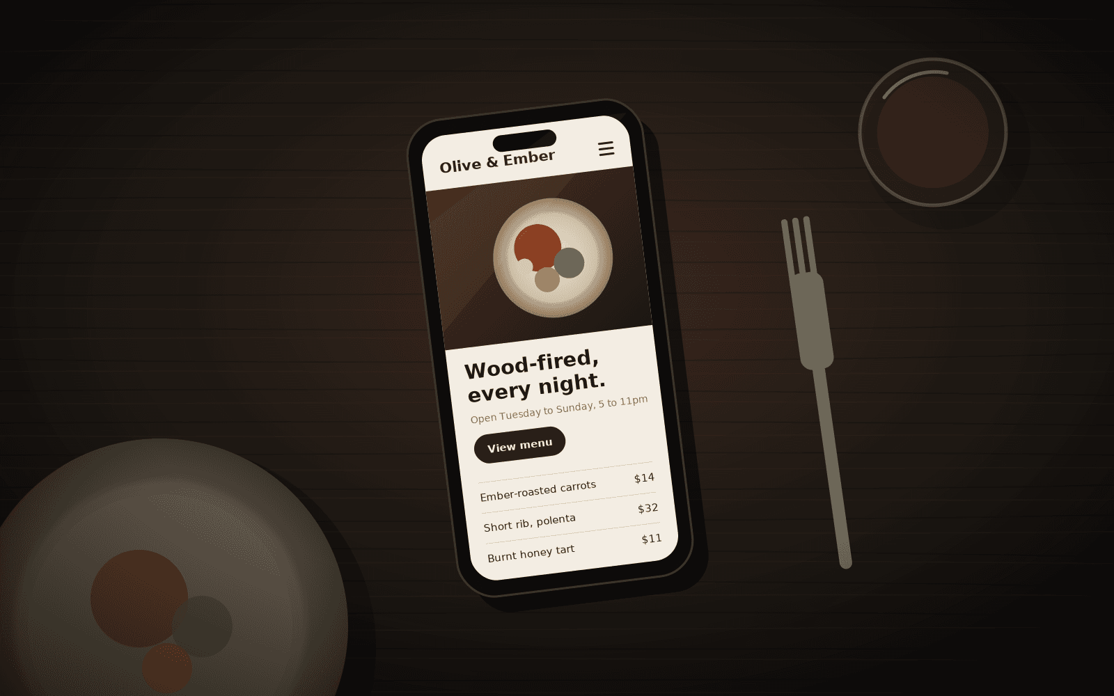 A restaurant website mockup on a phone next to a plate of food.